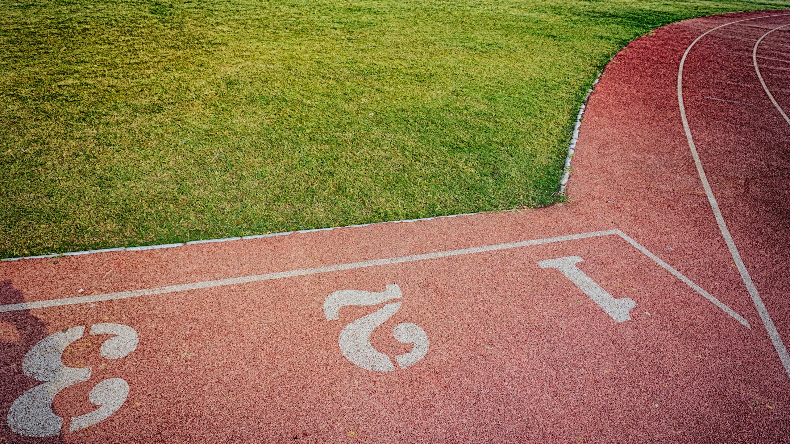 A bird's-eye view of a vibrant outdoor running track and lush green sports field.